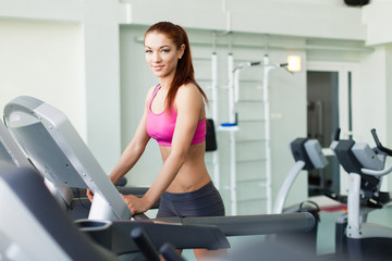 Fototapeta na wymiar fitness model runs on treadmill, is engaged in fitness club