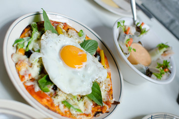 Pizza with fresh egg and basil leaves