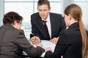 Fototapeta premium Agent signing documents with couple women