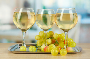 White wine in glass on salver on room background