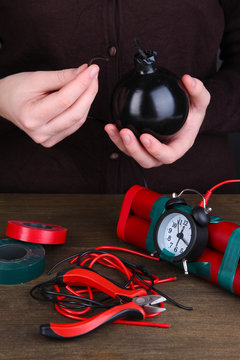 Human makes timebomb on wooden table on black background