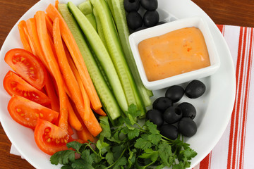 Assorted raw vegetables sticks in plate on wooden table close