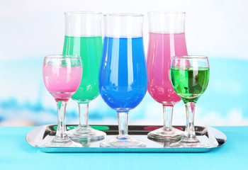 Glasses of cocktails on table near pool