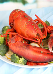 Red lobster on platter with vegetables on table close-up