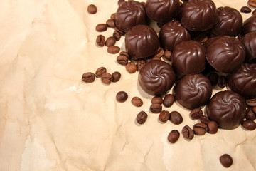 Chocolate candies and coffee beans, on beige paper background