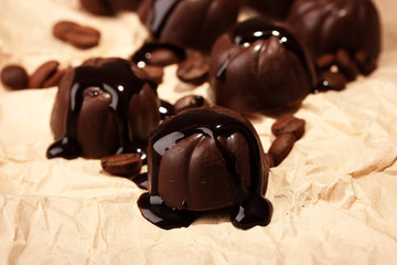 Chocolate candies and coffee beans, on beige paper background