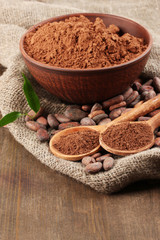 Cocoa powder and cocoa beans on wooden background