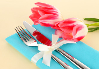 Festive dining table setting with tulips on beige background