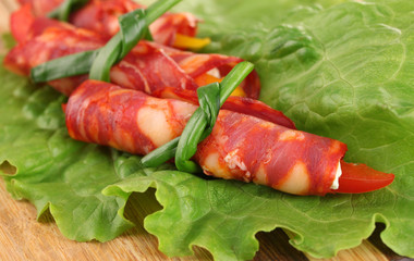 Salami rolls on wooden board, close up