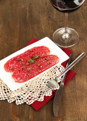 Tasty salami on plate on wooden table close-up