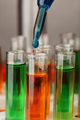 Laboratory pipette with drop of color liquid over glass test