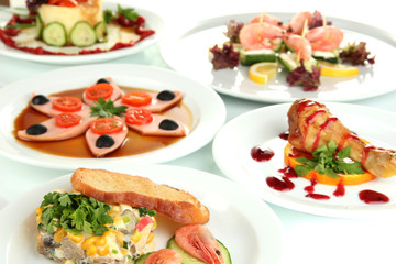 Small portions of food on big white plates close up