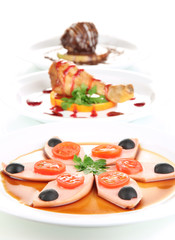 Small portions of food on big white plates isolated on white