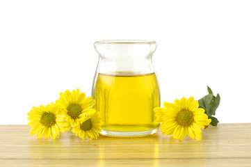 bottles of essential oil and yellow flower over wooden board background