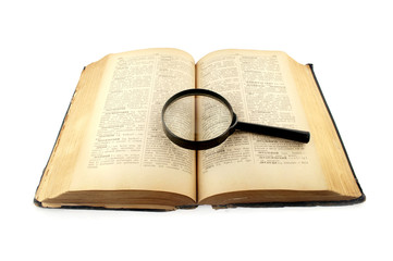 Obraz premium old dictionary book with a magnifying glass isolated on white b