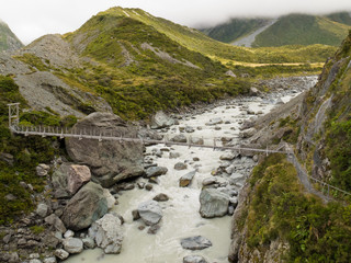 Swing bridge over mountain river in New Zealand