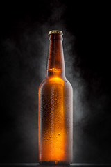 Cold beer bottle with drops, frost and vapour on black - obrazy, fototapety, plakaty
