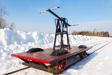 handcar on a narrow track in snow and blue sky