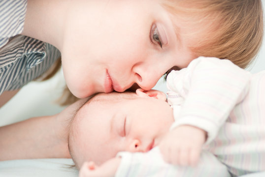 young mother kissing her slipping newborn baby