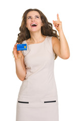 Obraz premium Happy young woman with credit card pointing on copy space