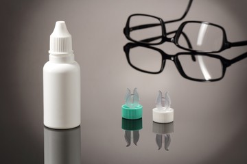 Kontaktlinsen mit Pflegemittel und Brille um Hintergrund
