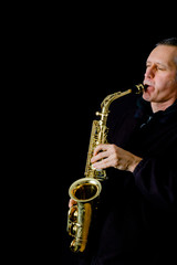 A Musician playing jazz music on his alto saxophone, on black background