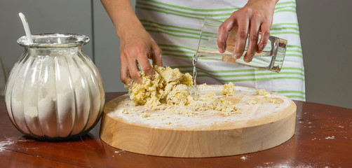Housewife adding water and kneading dough