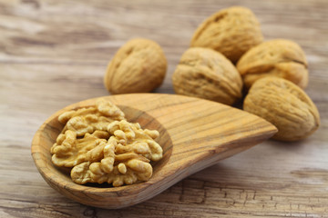 Walnuts with and without shell on wooden background