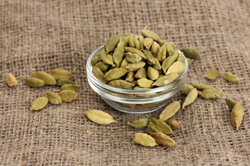 Green cardamon in glass bowl on canvas background close-up
