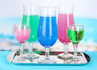 Glasses of cocktails on table near pool