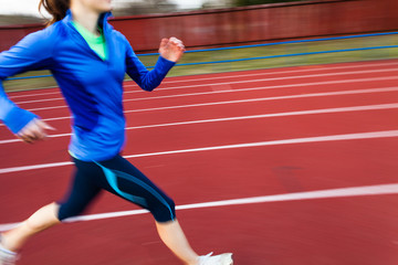 Fototapeta na wymiar Young woman running at a track and field stadium