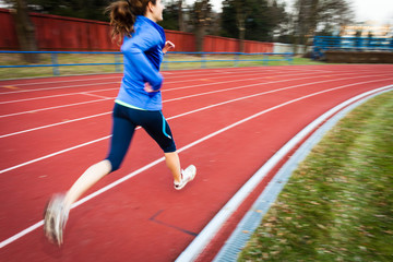 Obraz premium Young woman running at a track and field stadium