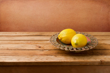 Fresh lemons on vintage plate on wooden table