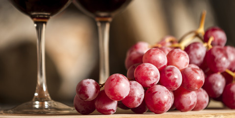 Uvas y copas de vino tinto de fondo.