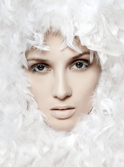 fashionable woman's face surrounded by white feathers