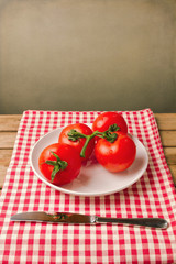Tomatoes on red tablecloth over grunge background