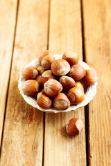 Hazelnuts on plate over wooden background