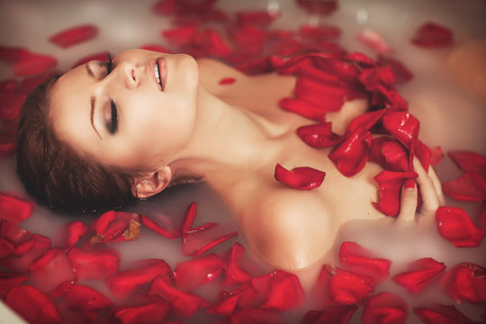 Woman in bath at spa in milk with roses petals