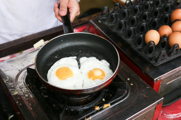A chef is cooking sunny-side up eggs
