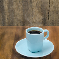 Blue cup of black coffee on a wooden table