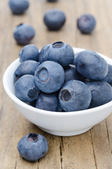 bowl of fresh blueberries on a wooden background