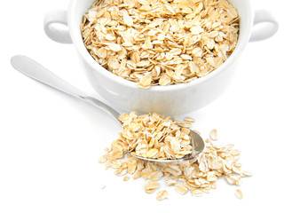 Oat flakes in bowl and spoon on white background