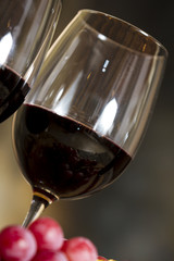 Copas de vino tinto, botella uvas y corcho.