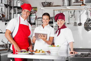 Happy Chefs Using Tablet Computer In Kitchen