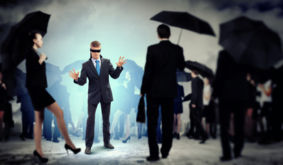 Businessman in blindfold among group of people