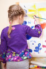 Small Caucasian child painting with brush and paint