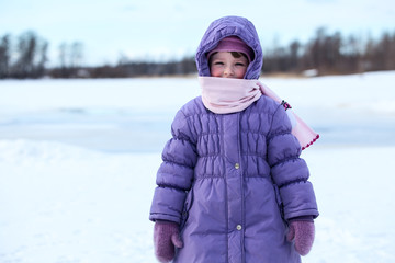 Wrapped in warm clothes small child standing outdoor in winter