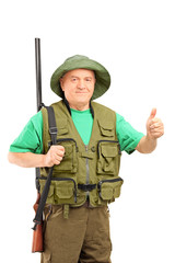A mature hunter holding a rifle and giving a thumb up