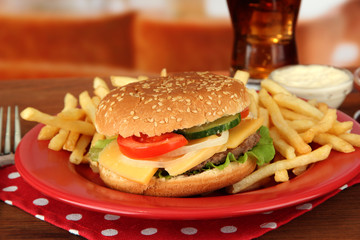 Tasty cheeseburger with fried potatoes and cold drink,