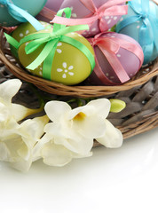 Bright easter eggs with bows in basket, isolated on white